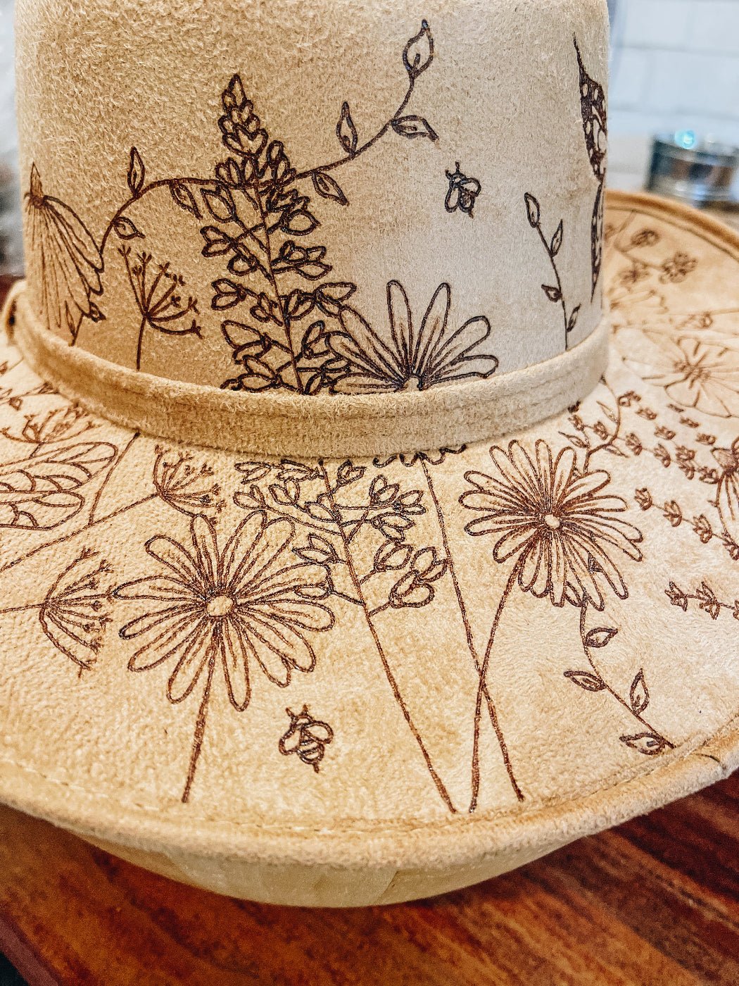 Cowgirl hat with hand-drawn wildflowers, butterflies, bees, and dragonflies around brim. Bluebonnet and daisy detail.
