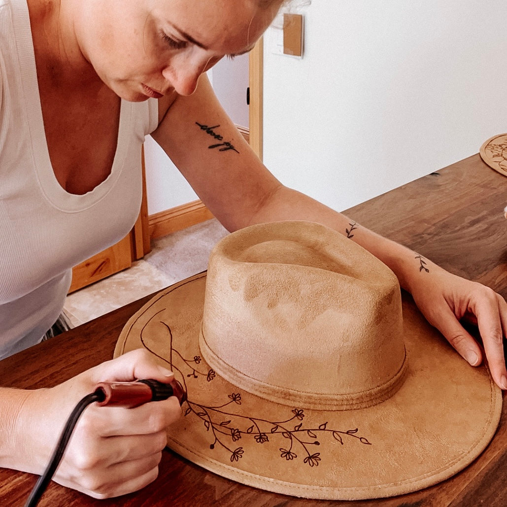 Wildflower Hat Studios artist in studio drawing on a hat