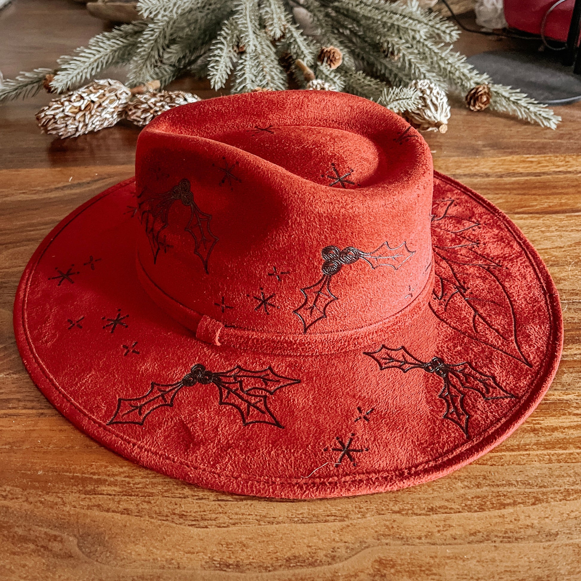 Red fedora with hand-drawn poinsettia, sparkle illustrations, and winter vines
