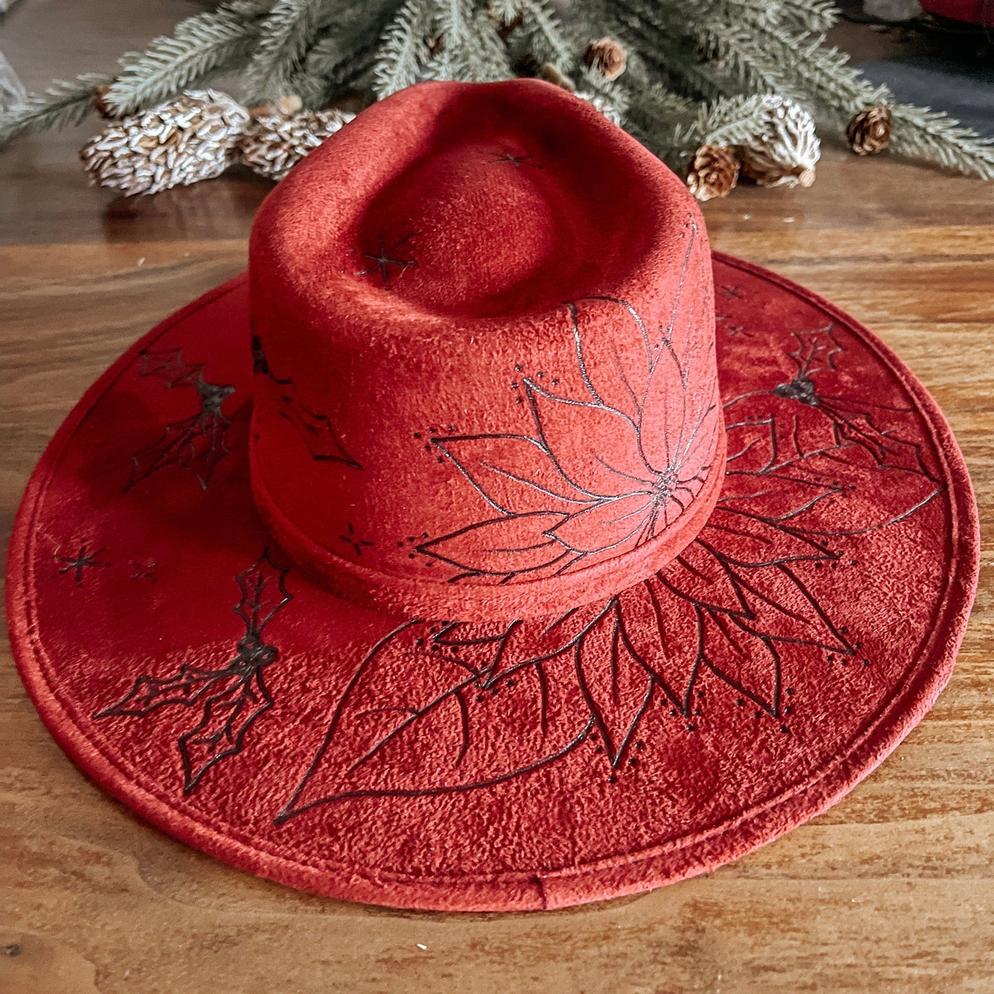 Red fedora with hand-drawn poinsettia, sparkle illustrations, and winter vines